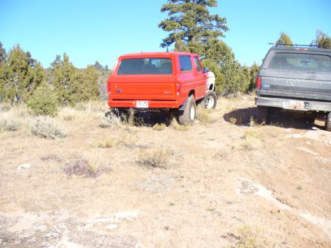 1979 Ford Bronco - Two SUVs parked in a dry, brushy landscape under a clear blue sky.
