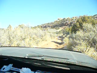 1979 Ford Bronco - View from inside a vehicle driving on a dusty, off-road trail through a desert-like environment.