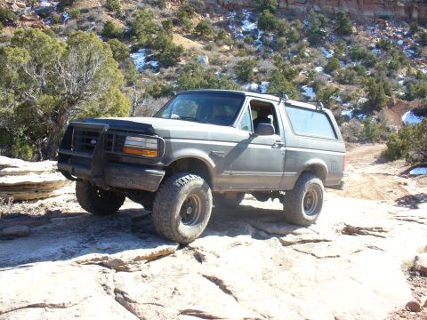 1979 Ford Bronco - Ford Bronco navigates a rocky trail in a desert landscape.