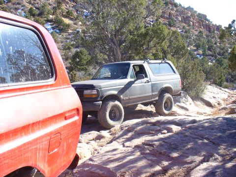1979 Ford Bronco - Two Broncos navigate a rocky, desert landscape under a clear sky.