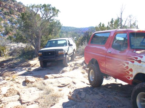 1979 Ford Bronco - Two SUVs navigate a challenging rocky terrain under a bright, clear sky.