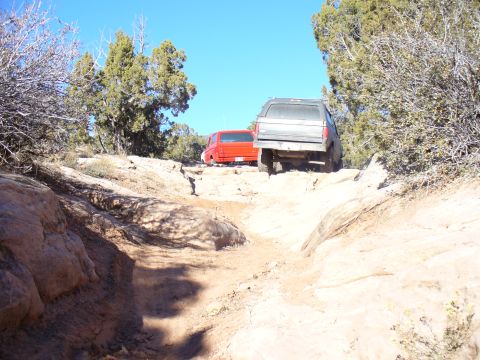 1979 Ford Bronco - Two SUVs tackle a challenging off-road trail, with one vehicle ahead and another following closely behind on the dusty, rocky terrain.