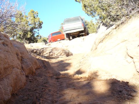 1979 Ford Bronco - Two SUVs navigate a challenging off-road trail with steep inclines and rocky terrain.