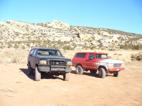 1979 Ford Bronco - Two Ford Broncos parked in a desert area with rocky hills in the background.