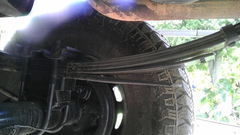 1989 Ford Bronco - Close-up of a vehicle's rear suspension system, focusing on the leaf springs and tire.