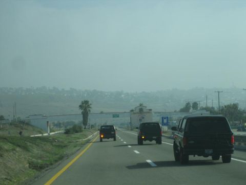 1986 Ford Bronco - Multiple SUVs are seen driving on a highway under a hazy sky.