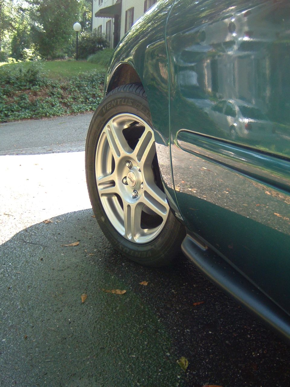 close-up of a green sedan's front wheel and side panel