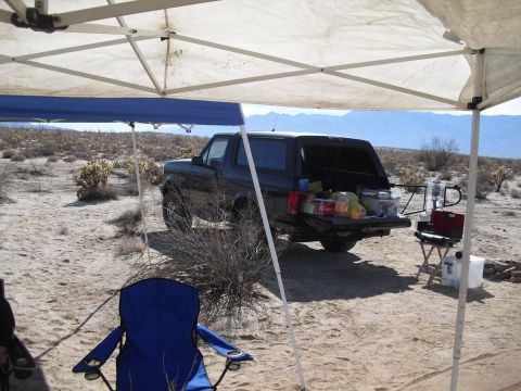 1986 Ford Bronco - Ford Bronco parked at a desert campsite with its tailgate open, loaded with camping supplies.