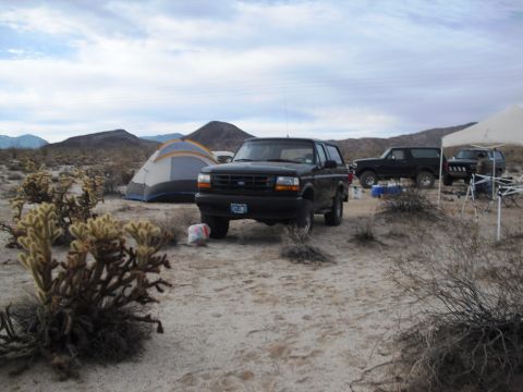 1986 Ford Bronco - A black 1992 Ford Bronco is parked at a desert campsite, with tents and mountains in the background.