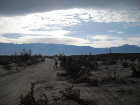 1986 Ford Bronco - Desert scene with mountains and a dirt road, several people.