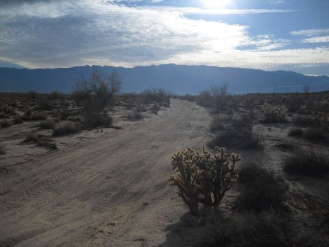1986 Ford Bronco - Dirt road winds through a desert landscape with mountains in the distance.