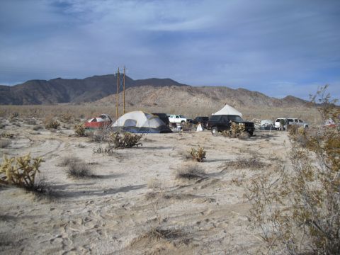 1986 Ford Bronco - A desert scene with multiple tents and vehicles set up, likely for an off-road event or camping trip.