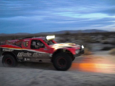1986 Ford Bronco - A red off-road truck with "Wide Open" graphics races across a desert landscape at dusk.