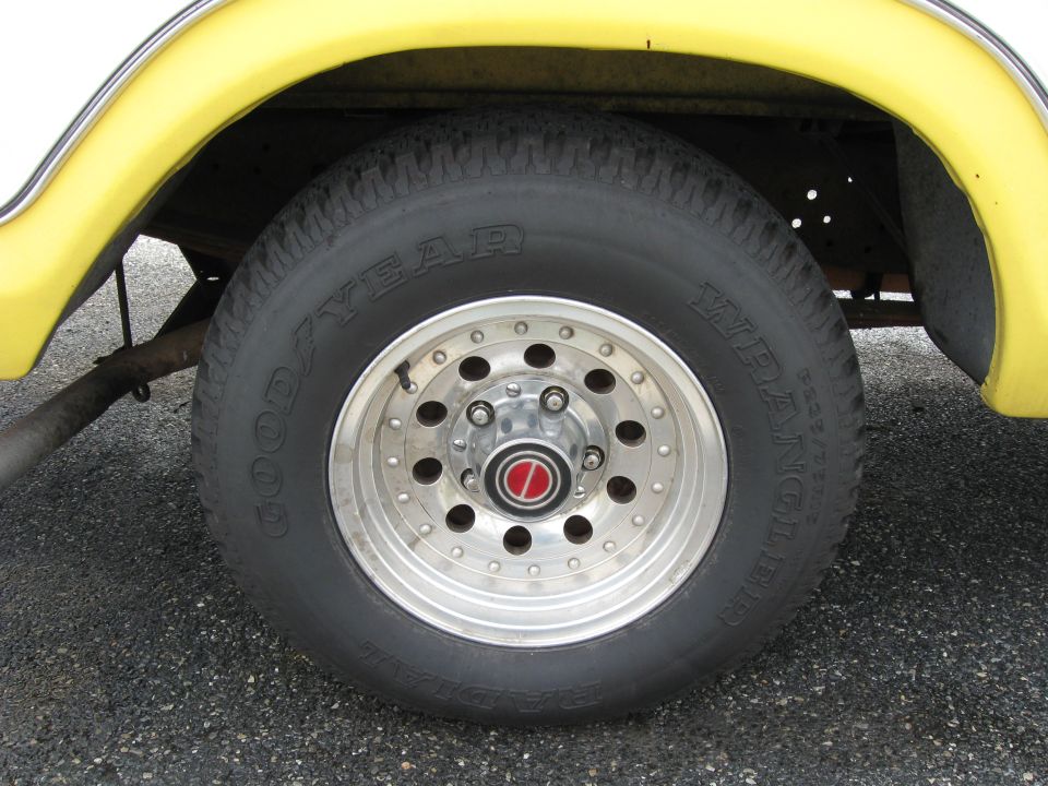 Goodyear Wrangler tire on chrome American Racing wheel under yellow fender