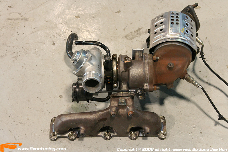 Turbocharger and catalytic converter assembly with exhaust manifold. Part is on a concrete floor