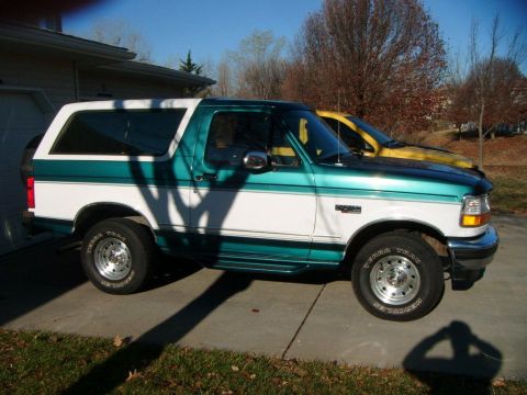 1996 Ford Bronco - Side view of a two-tone green and white 1996 Ford Bronco parked on a driveway.