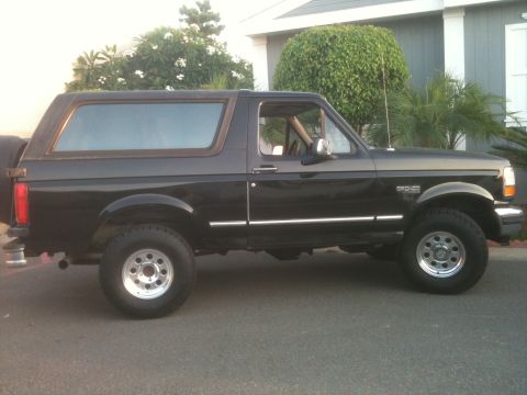 1993 Ford Explorer - Side profile of a black Ford Bronco with wood-grain trim around the windows.