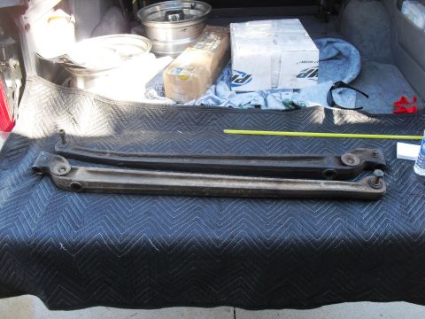 1986 Ford Bronco - Suspension control arms are laid out on a quilted mat in the cargo area of a vehicle.