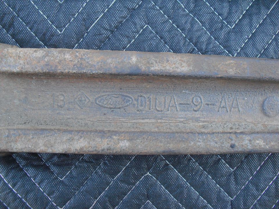 Close-up of a rusty metal part with embossed Ford logo and casting numbers D1UA-9-AA