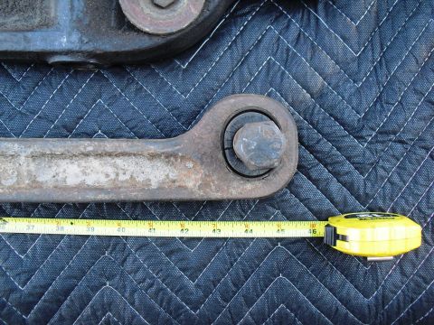 1986 Ford Bronco - A rusty suspension part is measured with a yellow tape measure against a quilted blue background.