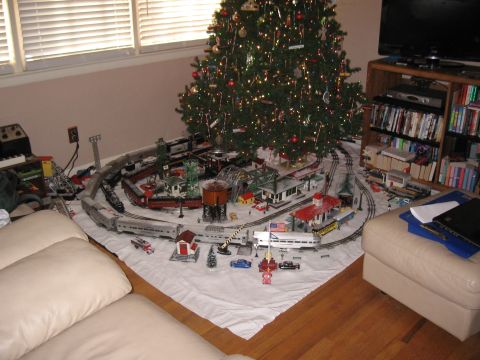 1994 Ford Bronco - A detailed model train set is set up around a Christmas tree, complete with buildings and scenery.