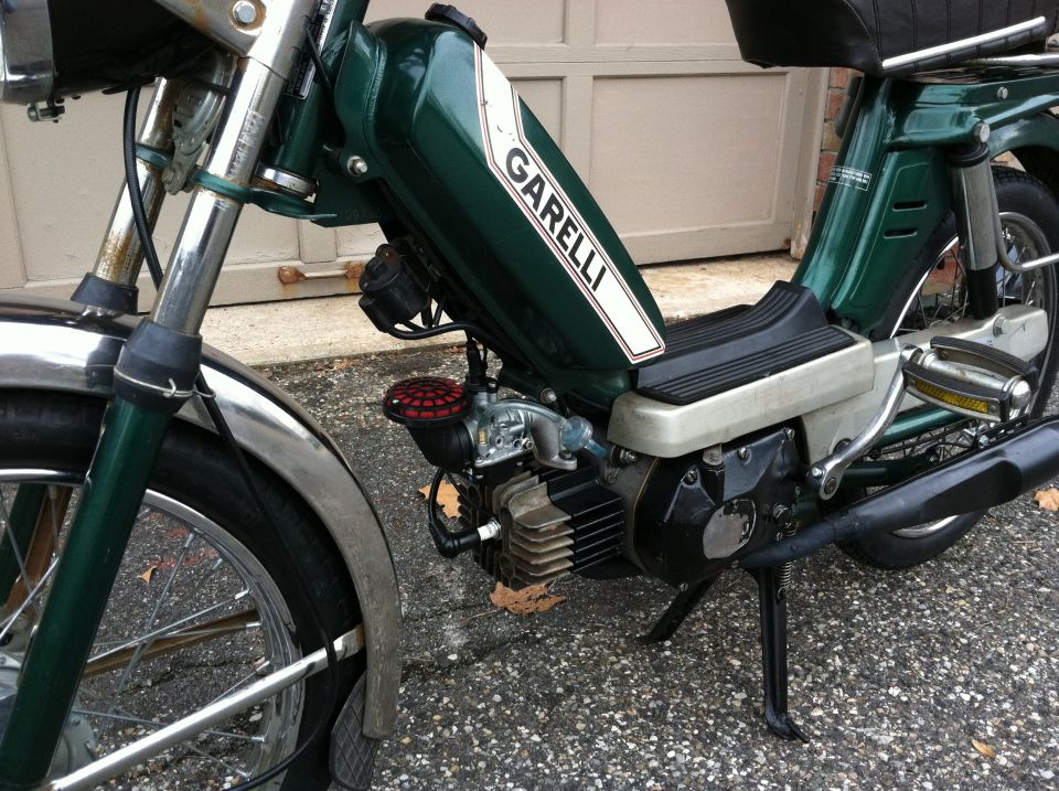 Green moped with white stripe and "GARELLI" text on the fuel tank. Engine and front wheel visible