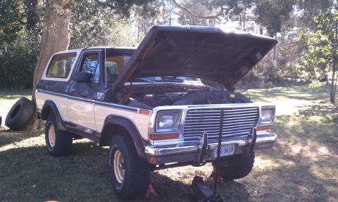 1979 Ford Bronco - A two-tone white and dark blue Ford Bronco sits outdoors with its hood open, revealing the engine bay.