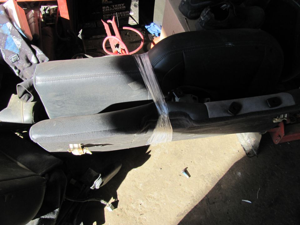 Vehicle seat with plastic wrap around it, in a garage setting