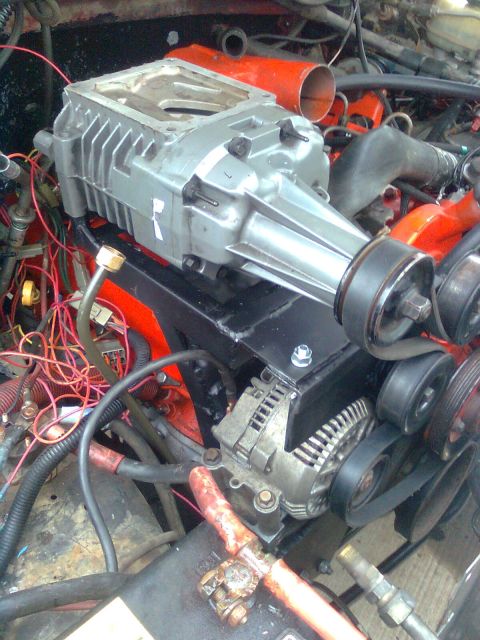1984 Ford Bronco - Close-up view of an engine bay with a supercharger installation, including various engine components and wiring.
