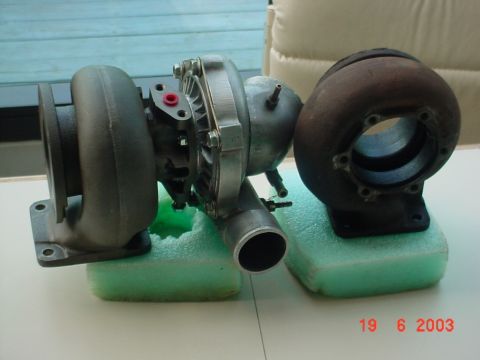 1987 Ford Bronco - A comparison of a new turbocharger next to a rusted, older model, both resting on green foam blocks.