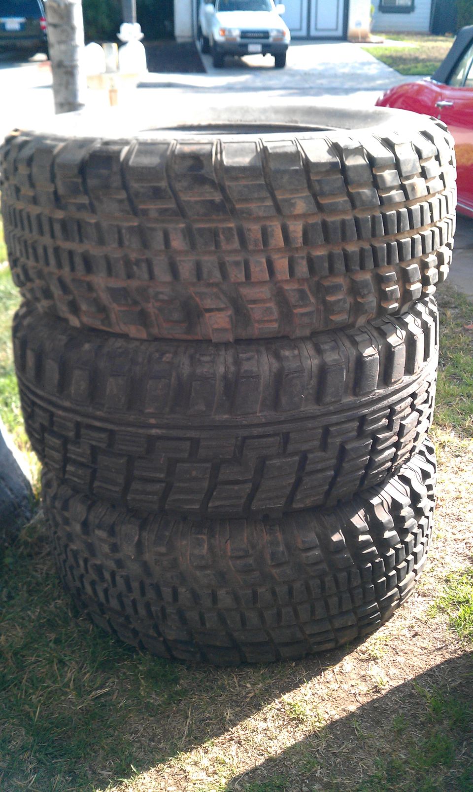 Stack of four used off-road tires with aggressive tread patterns