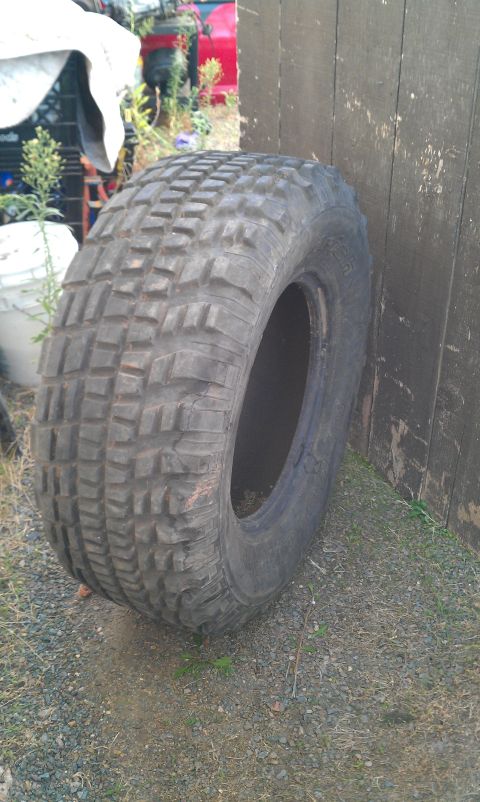 1992 Ford Ranger - A single off-road tire with aggressive tread is shown leaning against a weathered wooden fence.