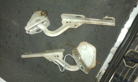 1992 Ford Ranger - Two automotive hood hinges are shown lying on a dark, textured surface.