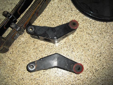1986 Ford Bronco - Leaf spring assembly and shackle parts shown on a speckled surface.