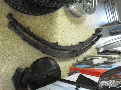 1986 Ford Bronco - A pair of vehicle leaf springs are shown with a tire and wheel, possibly for sale or storage.