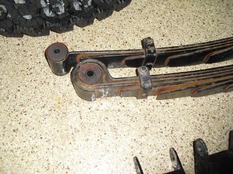 1986 Ford Bronco - Close-up of vehicle leaf springs and shackles, with a tire tread visible in the upper left corner.