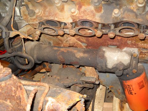 1988 Ford F-250 - Close-up view of a rusty engine exhaust manifold and an orange FRAM oil filter, indicating engine components.