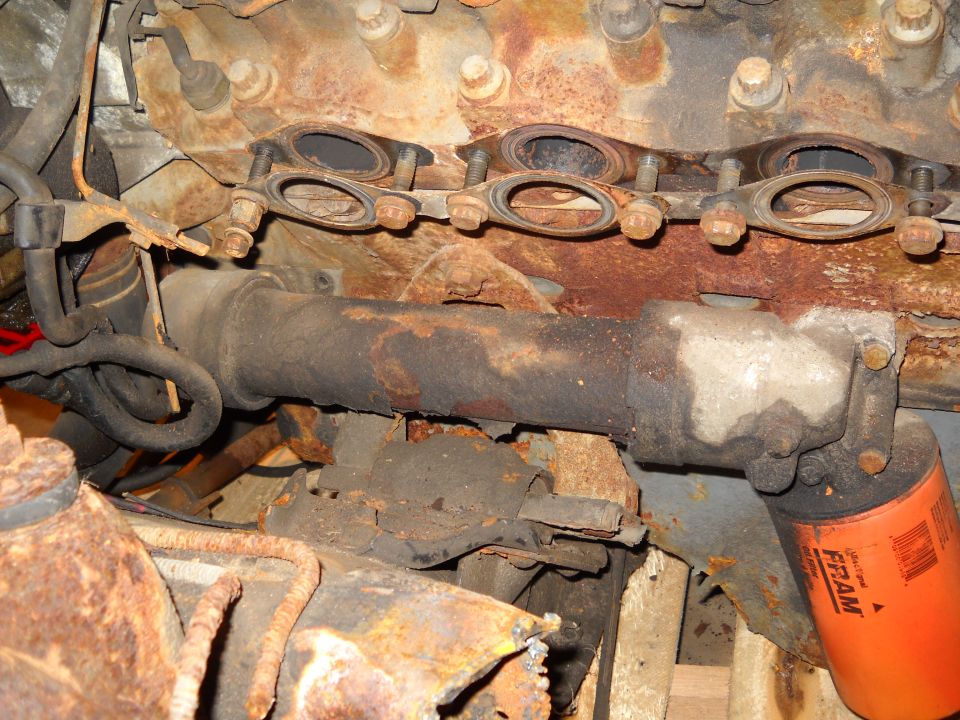 Engine exhaust manifold with gaskets and an orange FRAM oil filter