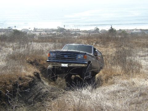 1989 Ford Bronco - This 1989 Ford Bronco navigates a challenging off-road terrain with the ocean visible in the distance.