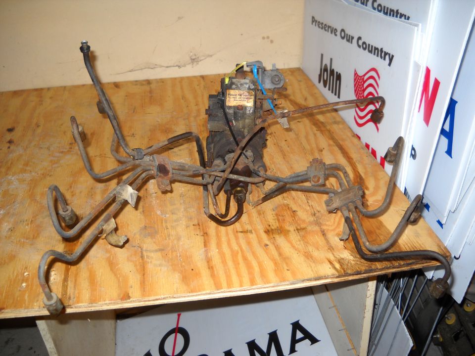 Diesel fuel injection pump with metal fuel lines, resting on a wooden surface