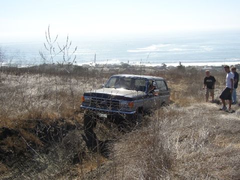 1989 Ford Bronco - 1989 Ford Bronco navigating rough terrain with the ocean in the background.