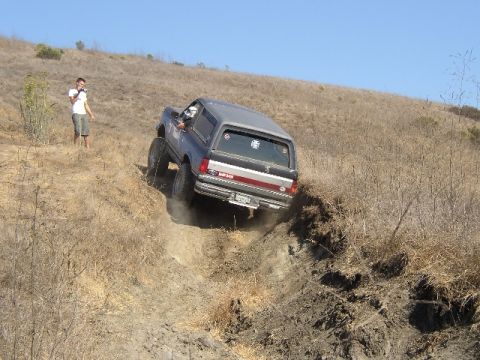 1989 Ford Bronco - A Ford Bronco navigates a challenging off-road trail on a sunny day.
