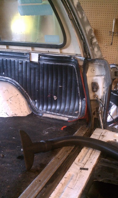 1978 Ford Bronco - Vacuuming the interior of a vehicle, focusing on the rear paneling and floor area.