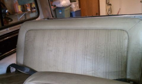 1978 Ford Bronco - The interior of a vehicle shows a rear bench seat with a striped fabric pattern.