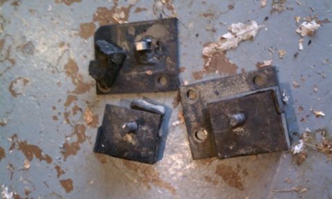 1978 Ford Bronco - Set of three engine mounts, likely for an older vehicle, resting on a stained concrete floor.