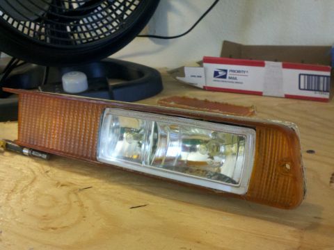 1978 Ford Bronco - A vehicle headlight assembly with an integrated amber turn signal is shown on a workbench.