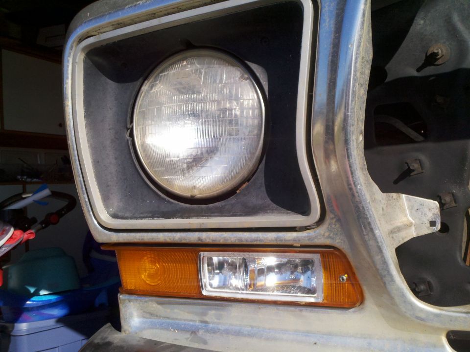 Close-up of a classic Ford truck/SUV headlight and amber turn signal.