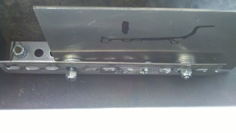 1978 Ford Bronco - A close-up view of a metal bracket with bolts and nuts, showing some text and markings.