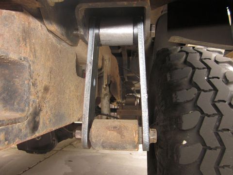 1985 Ford Bronco - Undercarriage view showing a leaf spring shackle and tire.