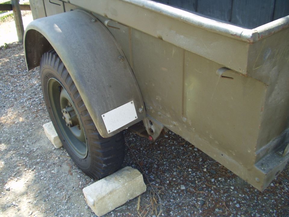 Olive drab trailer fender and wheel, supported by concrete blocks